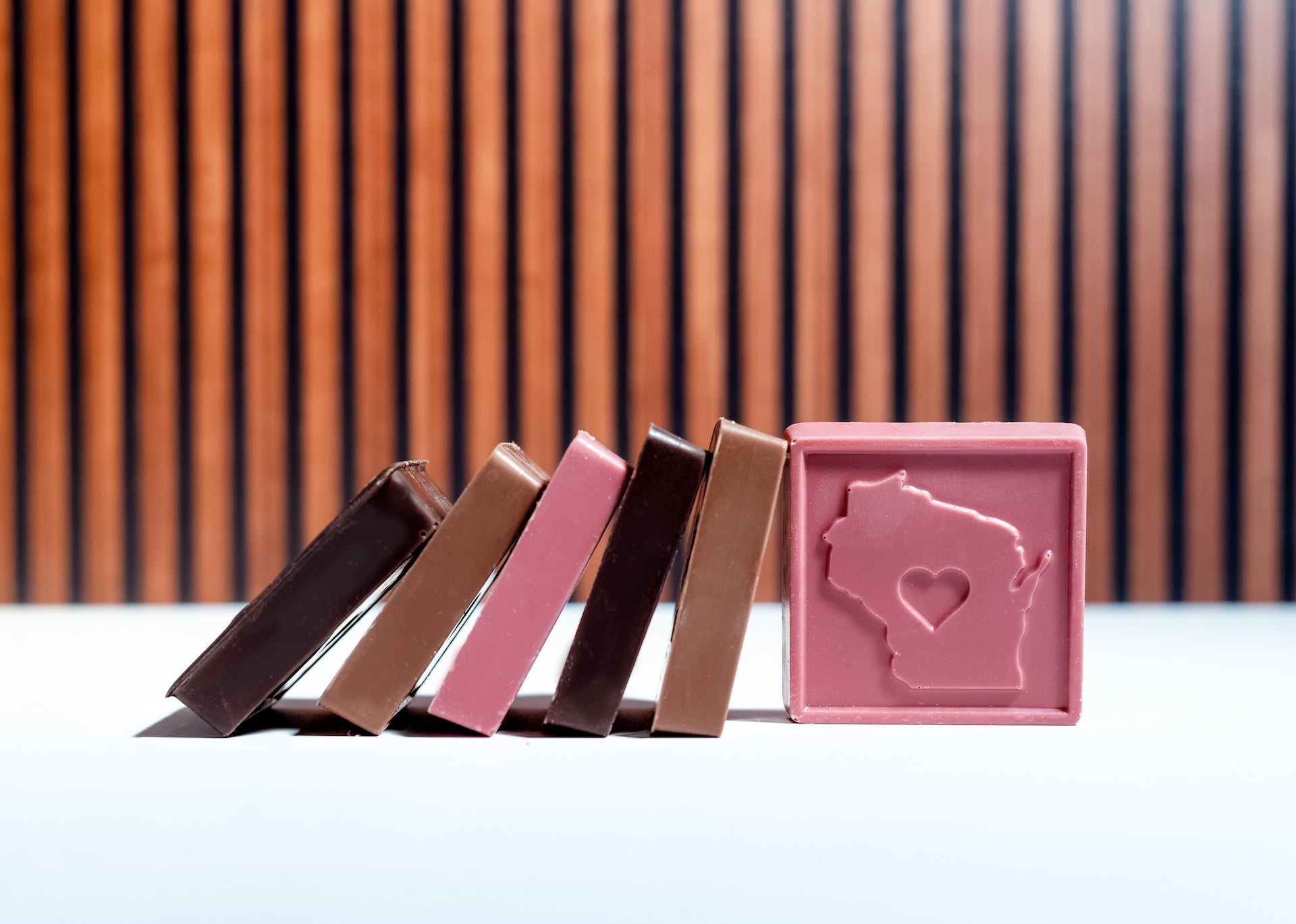 Chocolate bars with a pink mold shaped like the state of Wisconsin on a white surface.