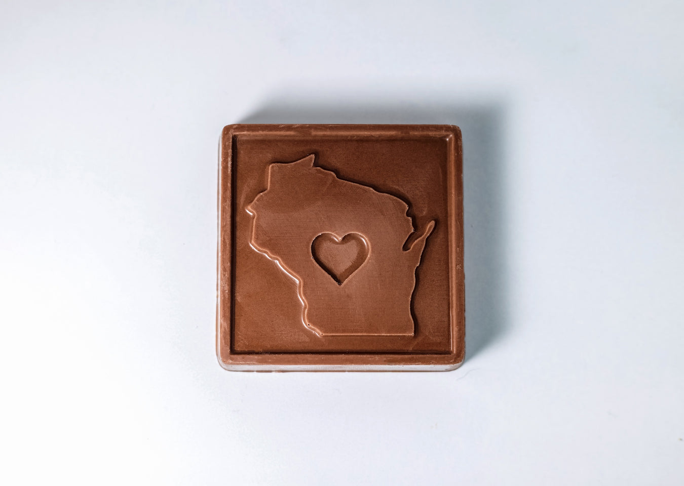 Milk chocolate bar with a cutout of Wisconsin featuring a heart in the center.