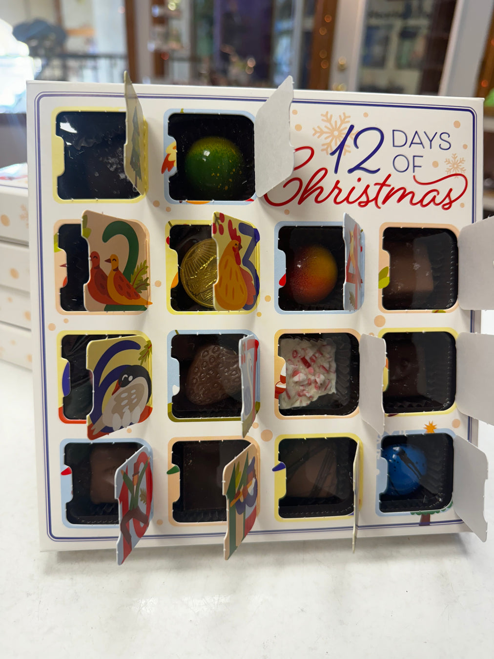 12 Days of Christmas chocolate advent calendar with open sections showing various chocolates.