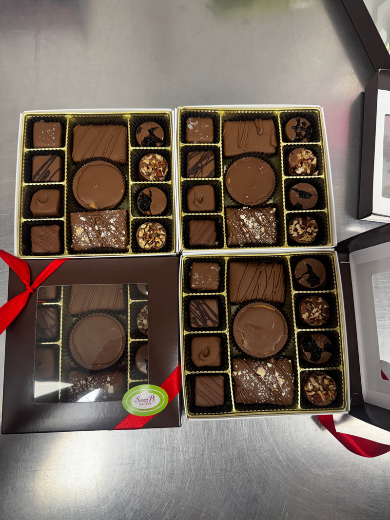Open box of assorted chocolates with a red ribbon on a metallic surface