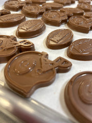 Close-up of several chocolate pieces shaped like football helmets, arranged on a light surface. The chocolates show embossed Green Bay football and helmet