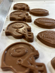 Chocolate figures shaped like football helmets and footballs arranged on a white surface.