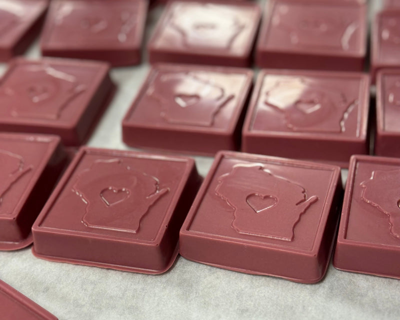 A photo of a chocolate bar with the shape of Wisconsin state and a heart cut-out in the center, indicating a tribute to the state.