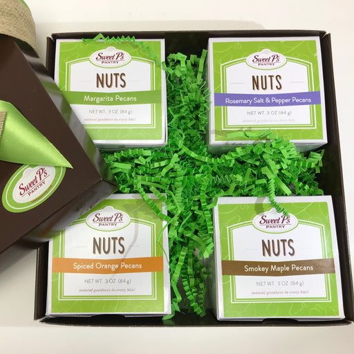 A gift box containing four bags of candied pecans in different flavors including Rosemary Salt & Pepper, Margarita, Spiced Orange, and Smokey Maple. Each flavor is labeled on the packaging.